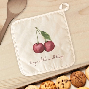 May include: A white cotton pot holder with a watercolor illustration of two red cherries and the text "cherry-ish the small things".