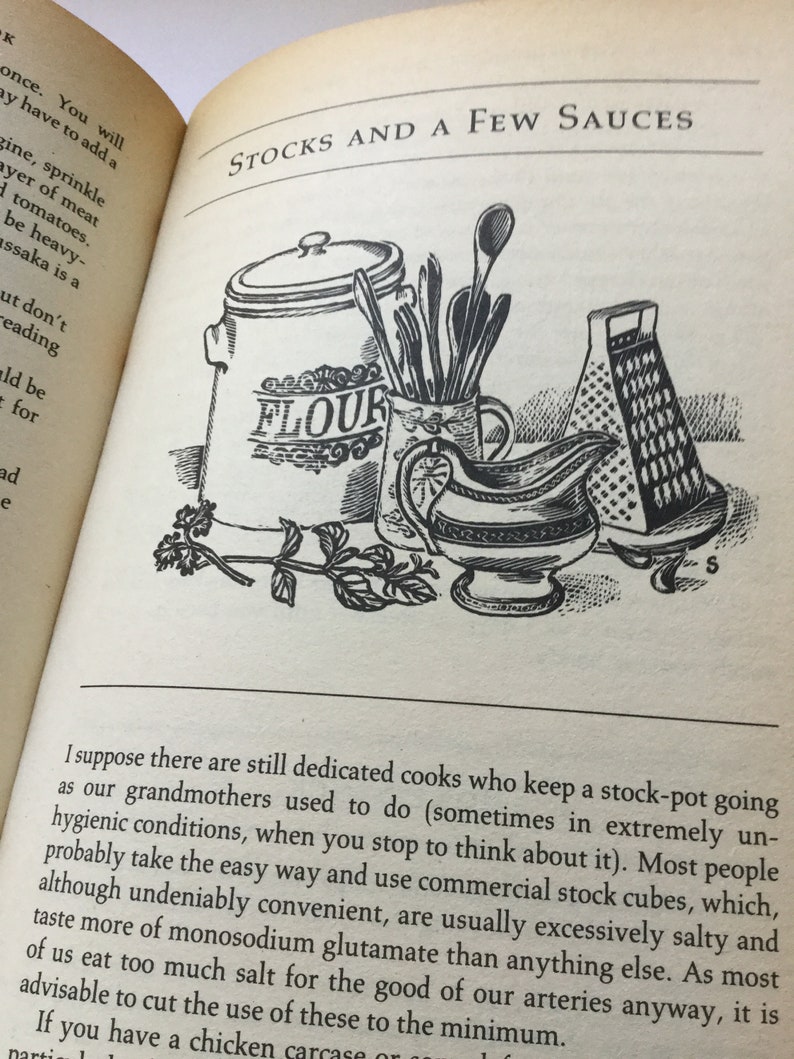 May include: A black and white illustration of kitchen utensils, a flour canister, and a grater. The illustration is from a vintage cookbook and includes the text "STOCKS AND A FEW SAUCES" and "FLOUR".