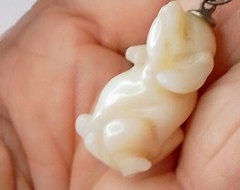 May include: A white porcelain pendant shaped like a rabbit, hanging from a silver chain.