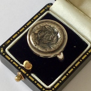Può includere: Un anello d'argento con un designo floreale dettagliato, presentato in una scatola per anelli in velluto nero con bordi dorati.