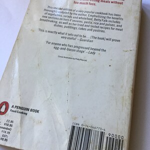 May include: The back cover of a Penguin paperback cookbook titled "Food/Cooking". The book is a revised edition of a popular cookbook that emphasizes the benefits of vegetables, salads, and whole foods. The cover features a white background with black text and a barcode. The price is listed as $10.95.