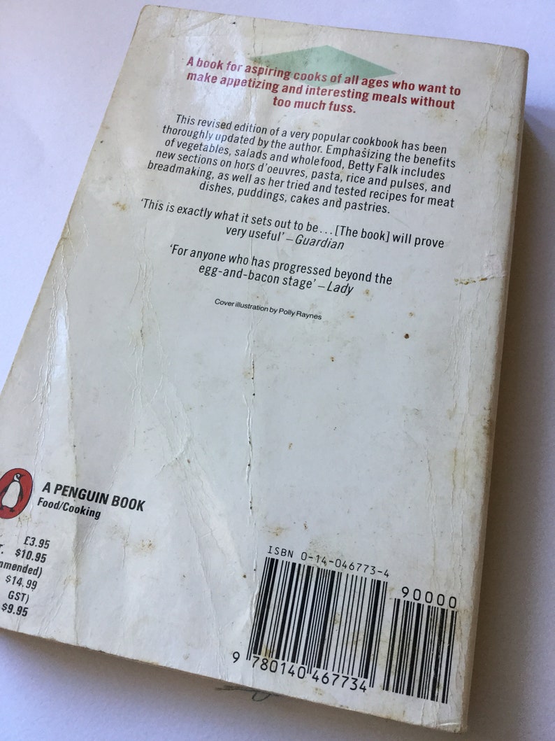 May include: The back cover of a Penguin paperback cookbook titled "Food/Cooking". The book is a revised edition of a popular cookbook that emphasizes the benefits of vegetables, salads, and whole foods. The cover features a white background with black text and a barcode. The price is listed as $10.95.