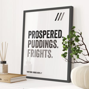 May include: A black framed print with the text "/// PROSPERED. PUDDINGS. FRIGHTS. YOUR OWN WORDS HERE ///" on a white background. The print is sitting on a shelf with a book and a vase with a plant.