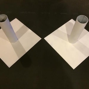 May include: Two white square bases with a white cylindrical tube in the center of each.