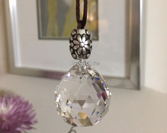 May include: A clear crystal ball hanging from a brown cord with a silver charm featuring a floral design. The charm has the text "MyOnlyChoice" on it.