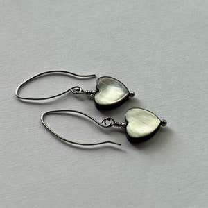 May include: A pair of silver heart-shaped earrings with a mother-of-pearl finish.