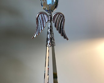 May include: A crystal angel ornament with a clear teardrop-shaped crystal and a blue crystal sphere at the top. The angel has silver wings.