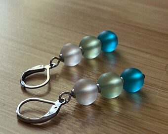 May include: A pair of silver hoop earrings with three frosted glass beads in shades of white, light green, and blue.