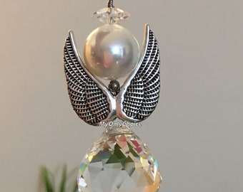 May include: A crystal suncatcher with a silver angel wing design and a white pearl bead. The suncatcher is hanging from a silver chain.