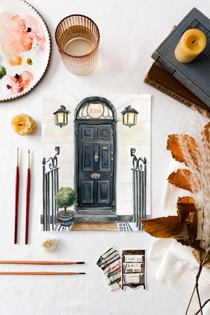 May include: A watercolor painting of a black door with a gold number "221B" above it. The door is surrounded by a white frame and has a small window above it. There are two black lanterns on either side of the door. The painting is on a white background.