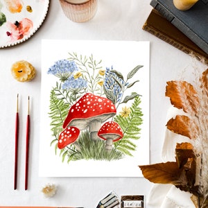 May include: Watercolor painting of red and white mushrooms with white spots growing in a cluster of green ferns and blue and yellow wildflowers.