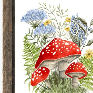 May include: Watercolor painting of red and white mushrooms with white spots, surrounded by blue and green wildflowers. The mushrooms are clustered together and have a whimsical feel.