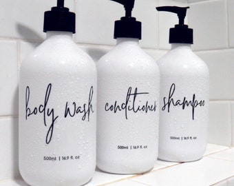 May include: Three white pump bottles with black labels and black pumps. The bottles are labeled "body wash", "conditioner", and "shampoo". Each bottle contains 16.9 fl. oz (500 ml).