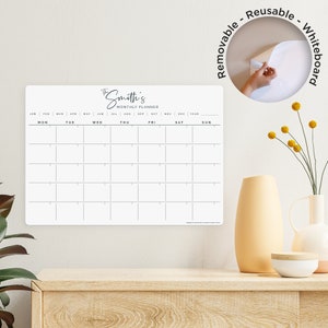 May include: White dry-erase monthly planner with the text "The Smith's Monthly Planner" at the top. The planner has a grid with the days of the week labelled at the top and the months of the year labelled at the bottom. The planner is removable and reusable.