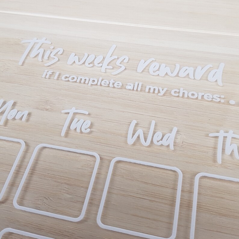 May include: White acrylic chore chart with the text "this week's reward if I complete all my chores:". The chart has seven days of the week labeled: Mon, Tue, Wed, Thu, Fri, Sat, Sun. Each day has a square for checking off chores.