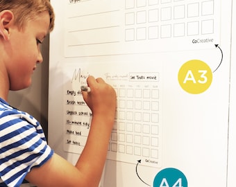 May include: A white chore chart with a grid for tracking daily tasks. The chart includes the text "Brush teeth" and "Unpack school bag." A child is writing on the chart with a marker. The chart is labeled "CoCreative."