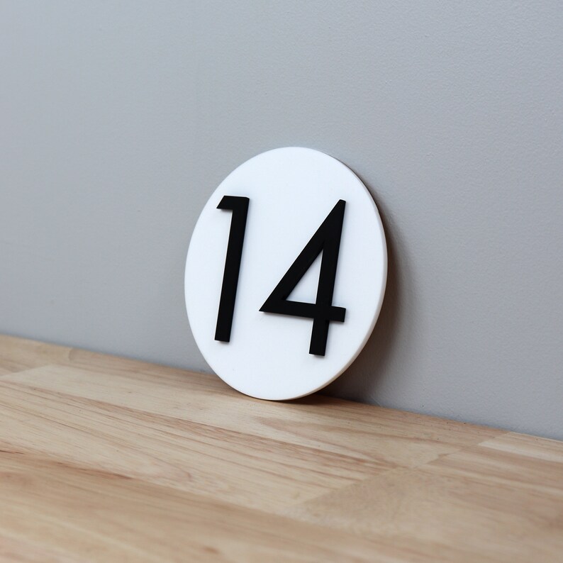 May include: White round sign with the number 14 printed in black.