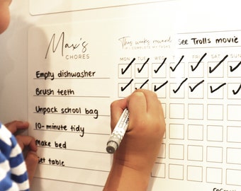 May include: A white dry-erase board with a chore chart for a child named Max. The chart includes tasks like "Empty dishwasher", "Brush teeth", and "Unpack school bag".  The chart also includes a calendar with checkboxes for each day of the week. The reward for completing all tasks is "See Trolls movie".