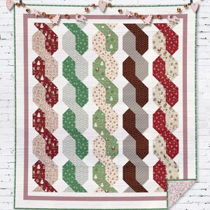May include: A white quilt with a red, green, and brown geometric pattern. The quilt is made up of repeating hexagons and is edged with a red and white striped border.