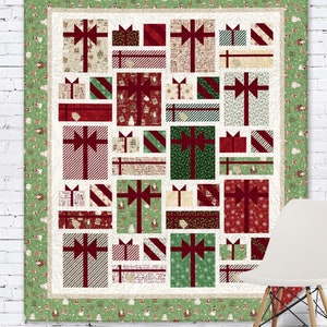 May include: A Christmas quilt with a patchwork design of presents in various colors and patterns. The quilt is framed with a green border featuring a repeating pattern of snowmen and Santa Claus.