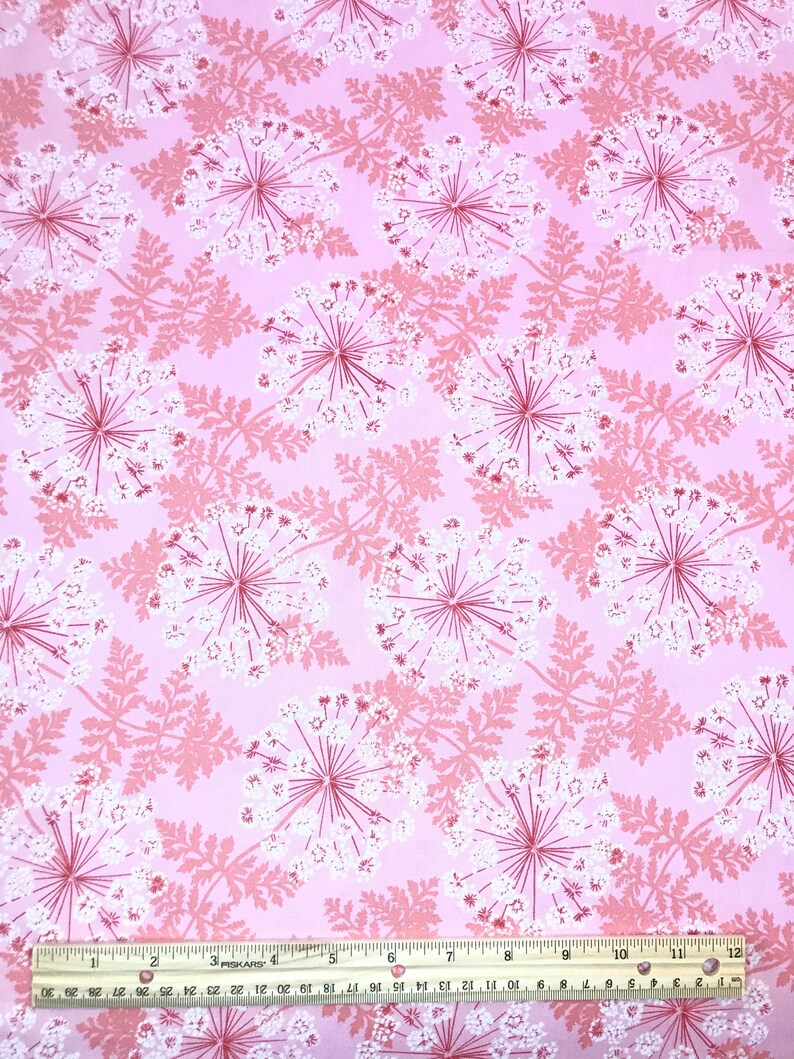 May include: Pink fabric with a repeating pattern of white and pink stylized flowers. A ruler is visible at the bottom of the image.