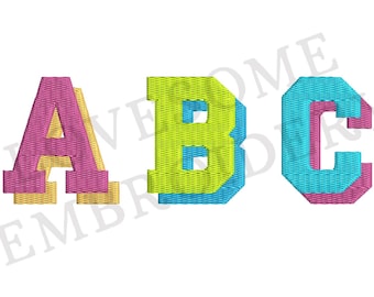 May include: A colorful embroidered design of the letters A, B, and C. The letters are in a bold, blocky font and are outlined in a contrasting color. The letters are in a rainbow color scheme, with A being pink and yellow, B being green and blue, and C being blue and pink.