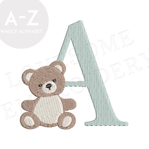 Op de afbeelding: Geborduurd ontwerp met de letter "A" in een lichtblauw geweven patroon, vergezeld van een bruine teddybeer. Het ontwerp maakt deel uit van een complete alfabetset, ideaal voor babyartikelen of kinderkamerdecoratie.