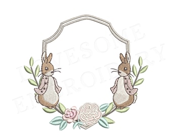 May include: Embroidered design featuring two brown rabbits with pink jackets, surrounded by green leaves and pink flowers. The rabbits are facing each other and are positioned on either side of a blank, white, octagonal frame.