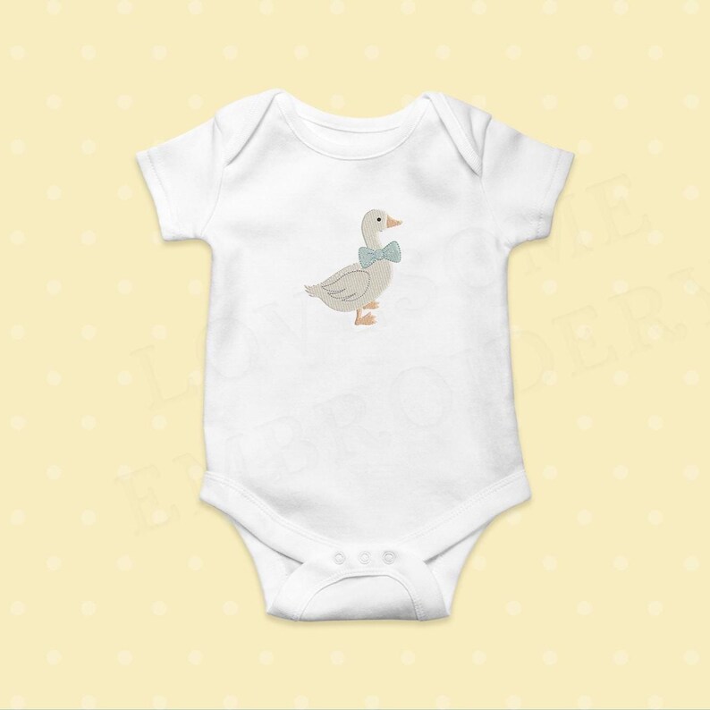 May include: White baby onesie with a light gray embroidered goose wearing a blue bow tie. The goose has an orange beak and feet. The onesie has short sleeves and a snap closure at the bottom. The background is a light yellow color.