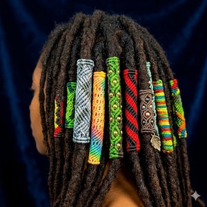 Könnte beinhalten: Seitenansicht einer Person mit Dreadlocks, die mit farbenfrohen Makramee-Haarwickeln verziert sind. Die Wickel weisen verschiedene Muster und Farben auf, darunter Grün, Rot, Schwarz und Regenbogenfarben, was der Frisur eine dekorative Note verleiht.
