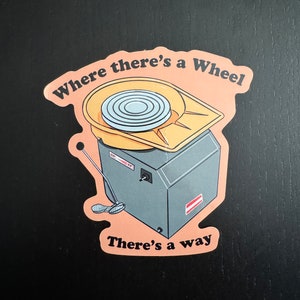 Puede incluir: Una pegatina con un torno de alfarería y el texto "Where there's a wheel there's a way".