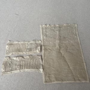 May include: Three pieces of antique white lace fabric with delicate embroidery. The fabric is worn and has a vintage look.