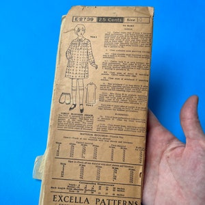May include: A vintage sewing pattern for a girl's bloomer frock and dress. The pattern is printed on a light brown paper with a blue background. The pattern includes instructions for making a dress with long or short sleeves and bloomers. The pattern is for size 10 and costs 25 cents. The pattern is from the Excella Corporation in New York.
