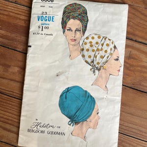 May include: A vintage Vogue pattern envelope 6606 for headwear, featuring illustrations of three different turban styles. The designs include a paisley print, a white turban with gold polka dots, and a solid teal turban, all by Halston of Bergdorf Goodman.