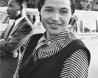 May include: Black and white photo of a woman wearing glasses and a striped shirt with a black vest. The woman is smiling and looking at the camera. The photo is captioned "Bygone Era".