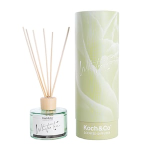 May include: A white tea scented diffuser with a clear glass bottle and wooden reeds. The bottle has a label that says "Koch & Co. Scented Diffuser" and "White Tea". The diffuser is packaged in a cylindrical box with a floral design and the text "White Tea" on the front.