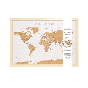 May include: A corkboard world map with a wooden frame. The map is white with brown corkboard outlining the countries. The text "Life is an adventure" is at the top of the map. The text "Create your own personalised travel map" is on the right side of the map.