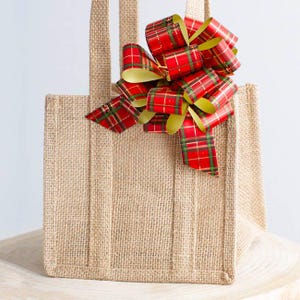 May include: A brown burlap tote bag with a red and gold plaid bow on top.