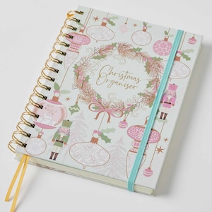 May include: A spiral bound Christmas organiser with a light blue cover featuring a wreath, baubles, and a nutcracker. The cover has the text "Christmas Organiser" in gold lettering.