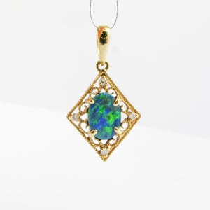 May include: A gold pendant with a green and blue opal gemstone set in a diamond-shaped frame with small diamonds around the edge.