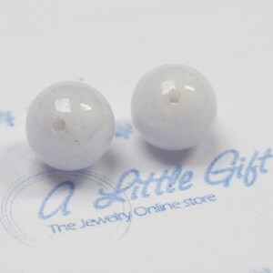May include: Two light blue round beads with a hole in the center. The beads are smooth and have a slight shine.