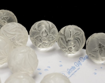May include: A collection of clear glass beads with intricate floral designs. The beads are smooth and translucent, with a subtle shimmer.