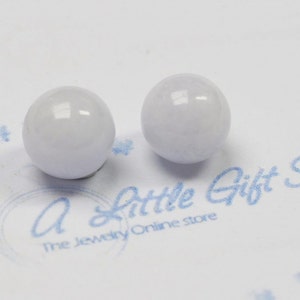 May include: Two white, round, smooth, polished beads. The beads are slightly translucent and have a subtle sheen.
