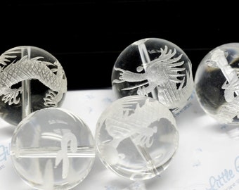 May include: A set of clear glass beads with etched dragon designs. The beads are round and have a smooth, polished finish.