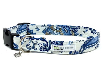 Könnte beinhalten: Hundehalsband mit blauem Paisley-Muster auf weißem Grund. Es hat eine schwarze Kunststoffschnalle, einen silbernen Metallring und einen kleinen Anhänger. Der Text "THE ECO DOG DESIGN COMPANY" ist auf dem Halsband aufgedruckt.