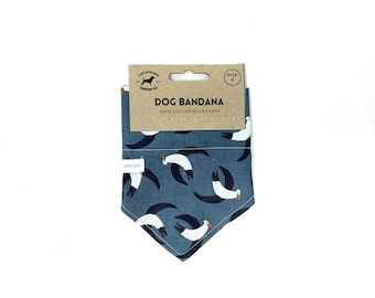May include: A dog bandana with a blue background and a pattern of white and black birds. The bandana is folded and has a cardboard tag that reads "Dog Bandana" and "Dog Collar Accessory". The tag also has the size "S".