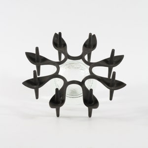 May include: Black metal candle holder with a starburst design and six candle arms. The holder has a clear glass bowl in the centre.