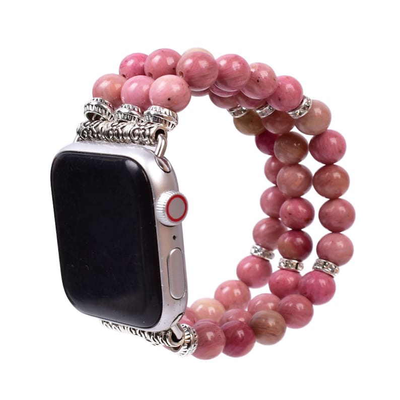 May include: A pink and silver beaded Apple Watch band. The band is made of multiple strands of pink beads with silver accents. The band is designed to fit a standard Apple Watch.