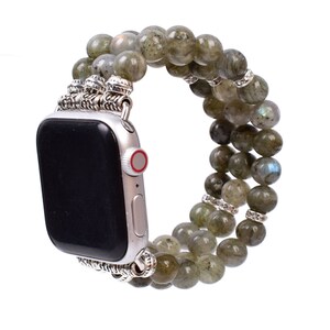 May include: A green and silver beaded Apple Watch band. The band is made of multiple strands of green beads with silver accents. The band is designed to fit an Apple Watch.