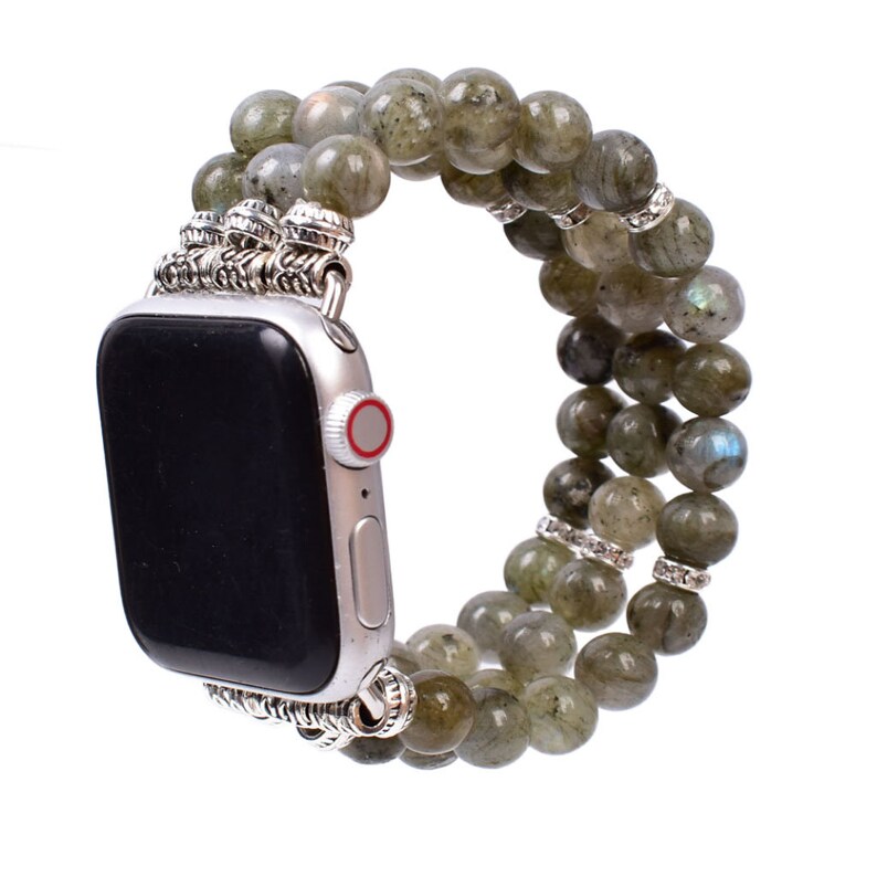 May include: A green and silver beaded Apple Watch band. The band is made of multiple strands of green beads with silver accents. The band is designed to fit an Apple Watch.
